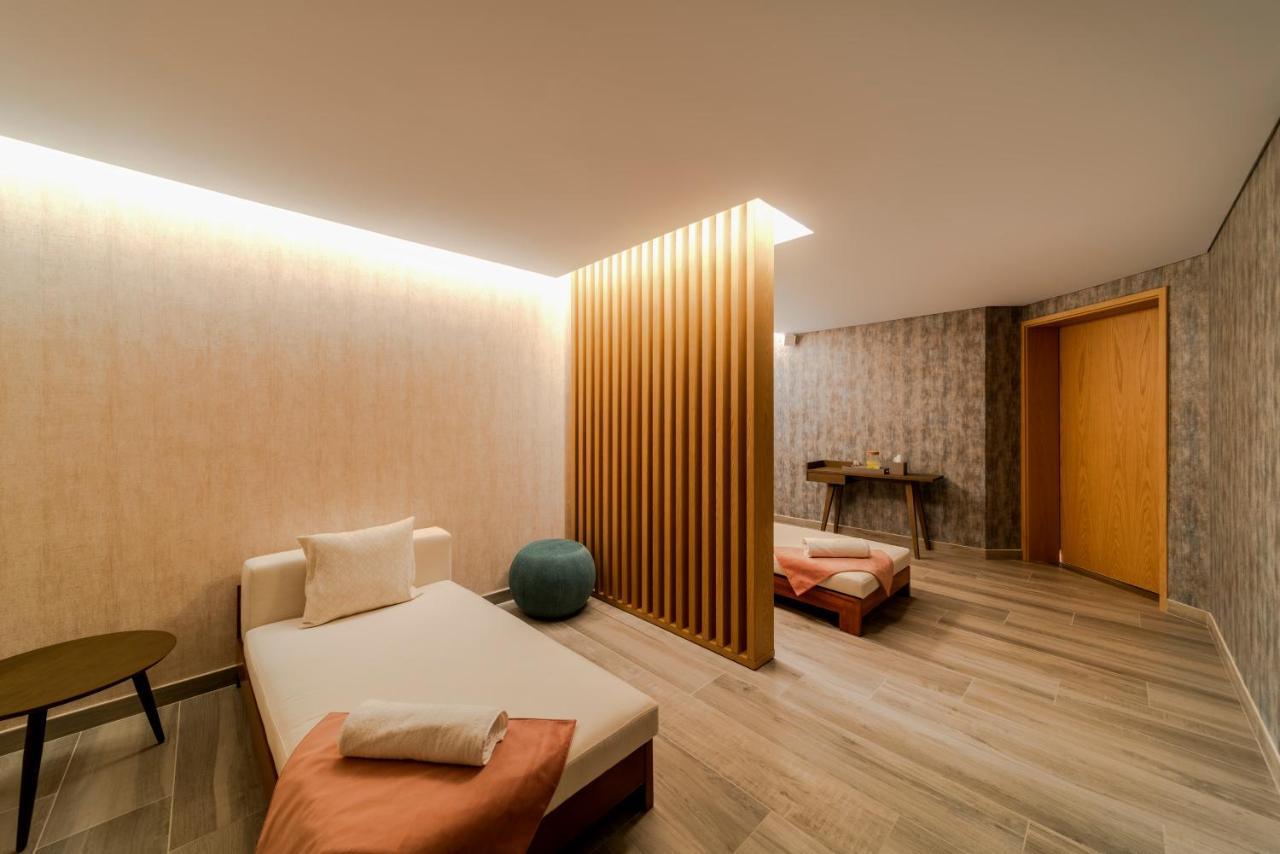 Five Jumeirah Village Dubai Exterior foto The photo depicts a calm and modern interior space, likely a relaxation or wellness area. It features a light-colored wood floor and soothing wall textures. 

On one side, there’s a daybed with soft cushions, accompanied by a small round table. A blu