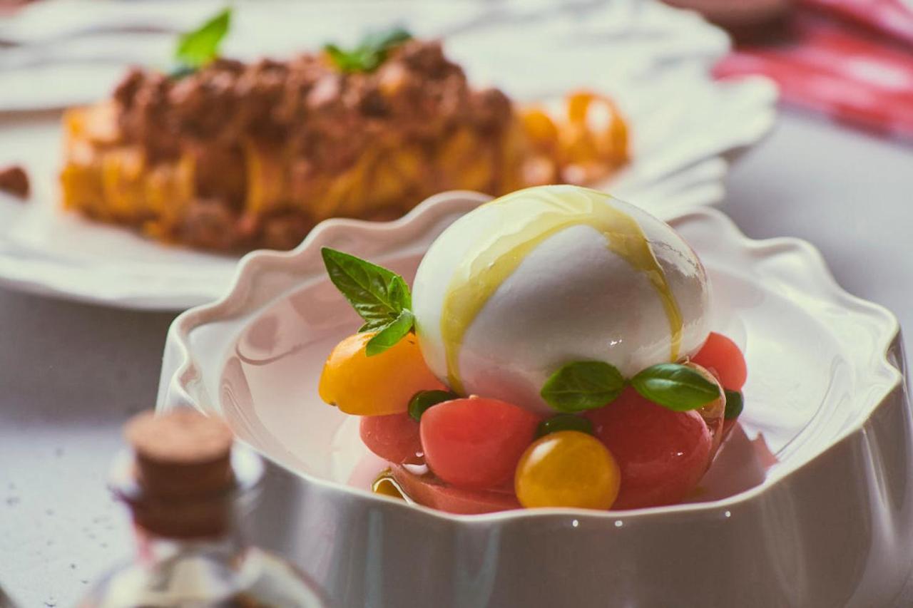 Five Jumeirah Village Dubai Exterior foto The photo showcases a beautifully presented dish featuring a large ball of fresh mozzarella cheese, sitting atop a colorful assortment of small tomatoes. The tomatoes are a mix of red and yellow, creating a vibrant visual contrast. Fresh basil leaves