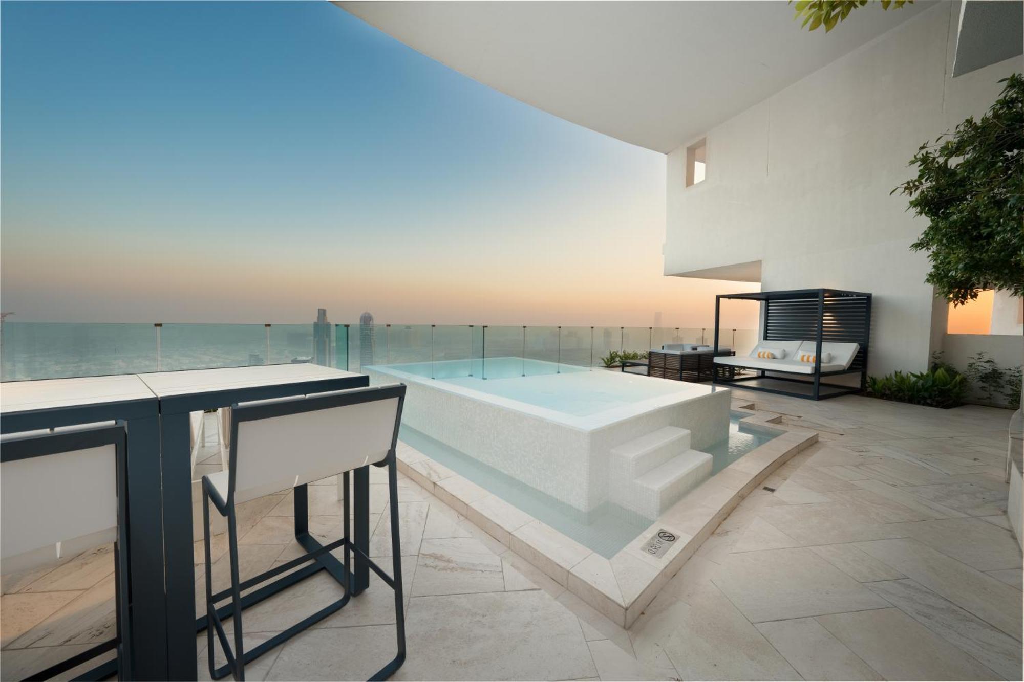 Five Jumeirah Village Dubai Exterior foto The photo depicts a luxurious outdoor space featuring a small infinity pool or hot tub that overlooks a scenic view. There is a stylish seating area nearby with modern furniture, including a table and chairs. The surroundings have a minimalist design