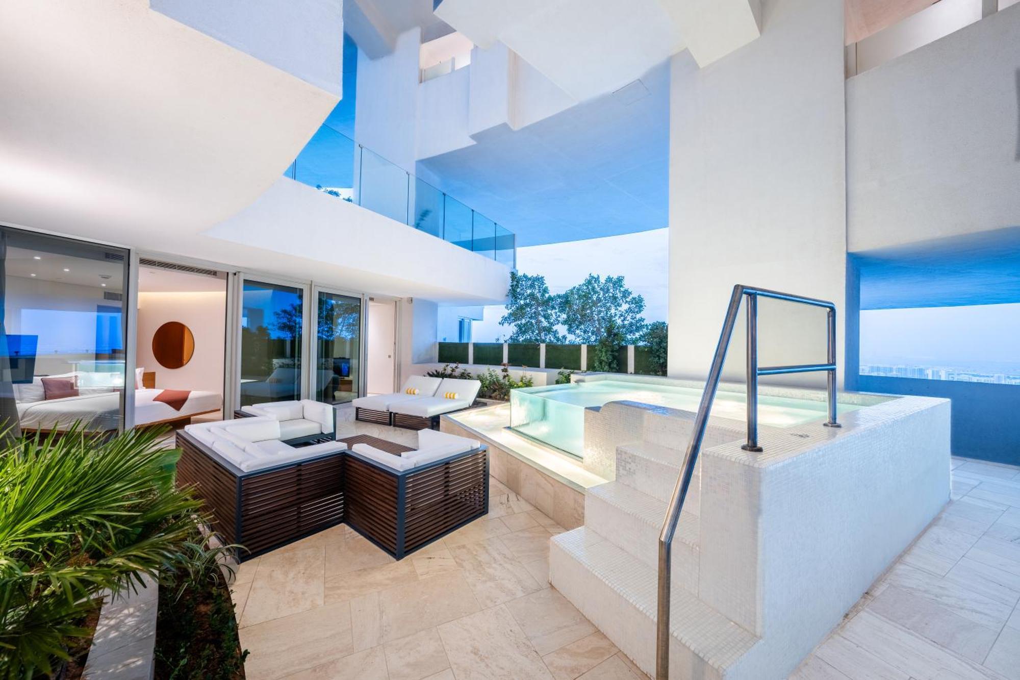 Five Jumeirah Village Dubai Exterior foto The photo shows a modern and stylish outdoor area that appears to be part of a contemporary residence. It features a seating arrangement with a lounge set made of dark wood and cushions, providing a comfortable space for relaxation. Nearby, there is 